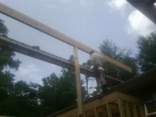 Carpenter setting a ridge beam over a new addition frame — Ice Dam Removal by Roofing Brothers in Middle Village