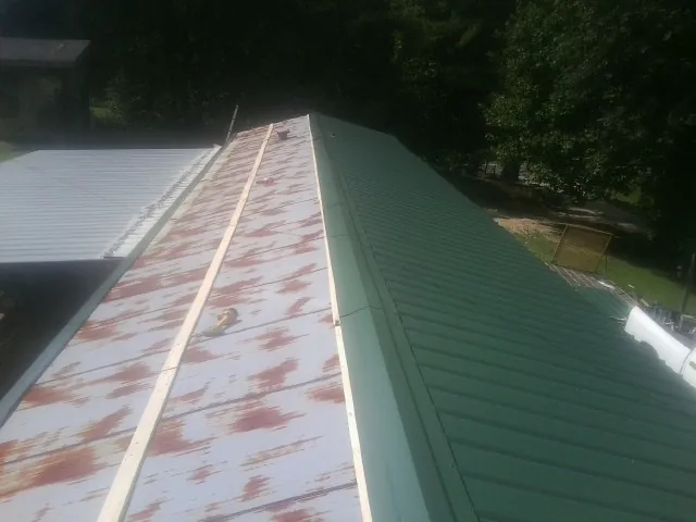 Old rusted panels beside newly installed green metal roofing — Wind Damage Roof Repair by Roofing Brothers in Middle Village