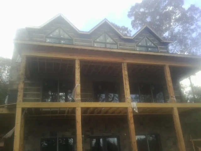 Dormers and porch framing on a large log home under construction — Roof Coating work by our crew in Middle Village