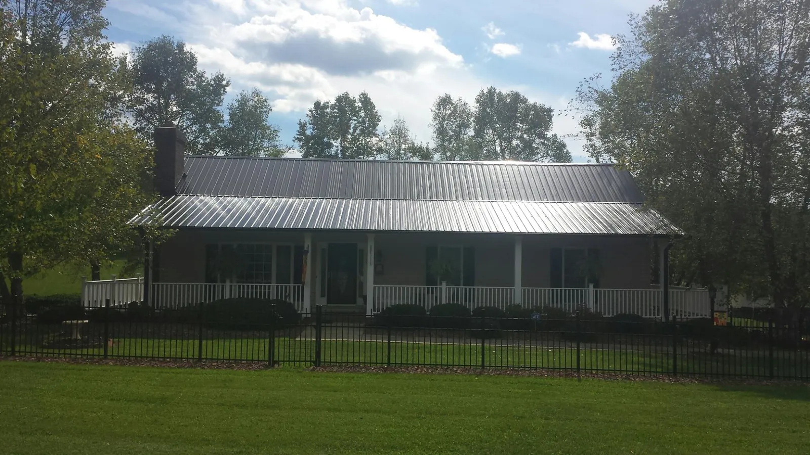 Gray metal roof on a brick ranch with a full width front porch — Gutter Guard Installation work by our crew in Middle Village