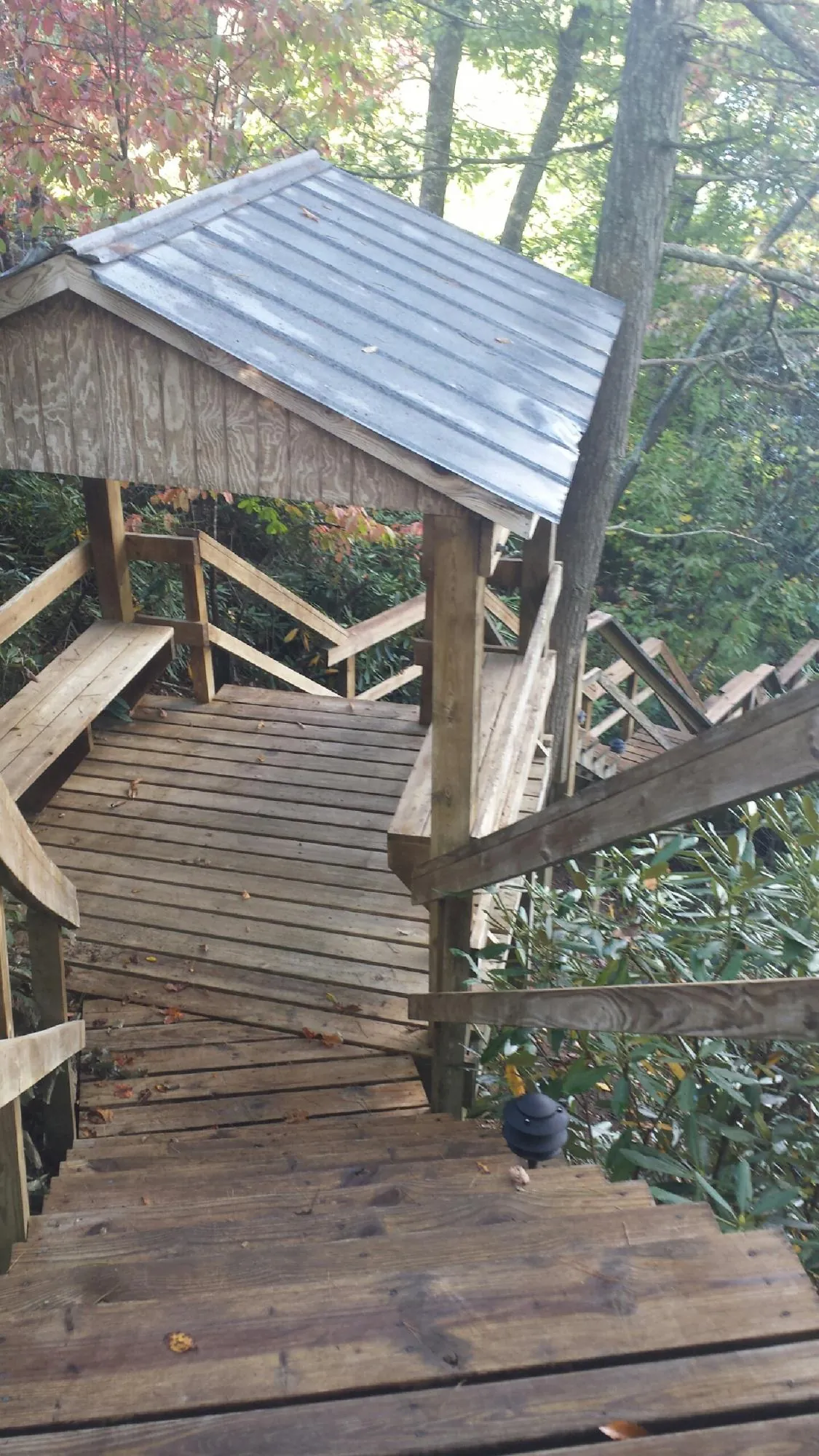 Metal roofed shelter over wooden steps on a wooded walkway — Skylight Repair & Installation work by our crew in Middle Village